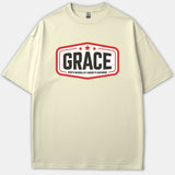 A beige Christian t-shirt featuring a red badge outline with three stars and black bold text that reads GRACE God's Riches At Christ's Expense.