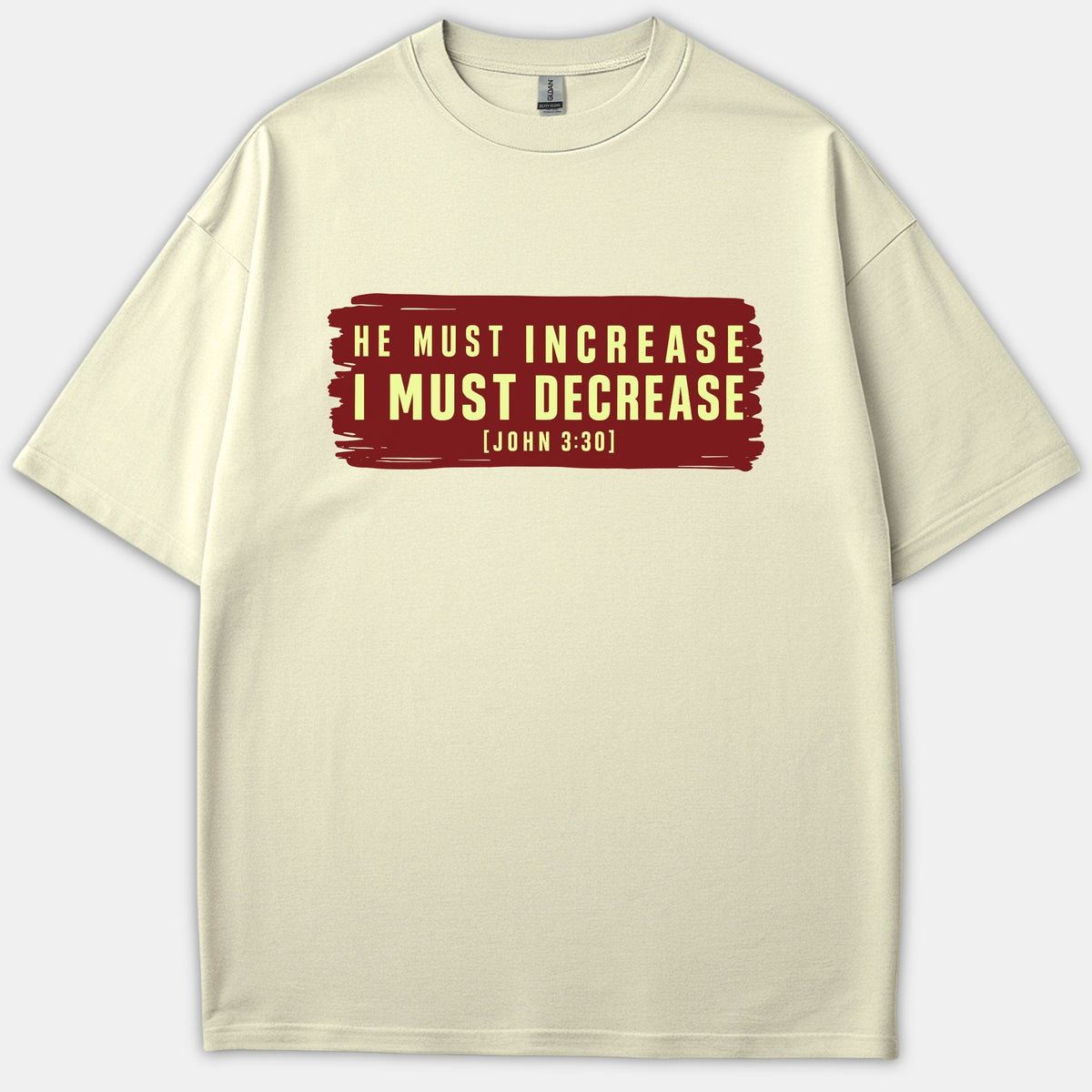 A beige Christian t-shirt featuring a red painted banner graphic printed with the scripture quote 'HE MUST INCREASE I MUST DECREASE [JOHN 3:30]' in yellow text.