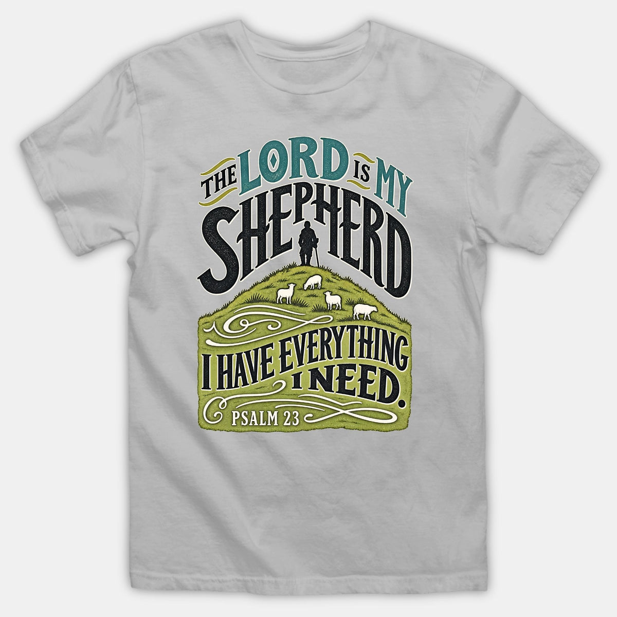 A gray T-shirt featuring vintage typography reading 'The Lord is my shepherd' above a green hill illustration with a shepherd and sheep.