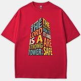 A red t-shirt featuring colorful 3D typography forming a tower shape with the scripture quote from Proverbs about the Lord being a strong tower.