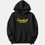 A black hoodie featuring the text Created (not evolved) printed in a bold yellow script font across the chest.
