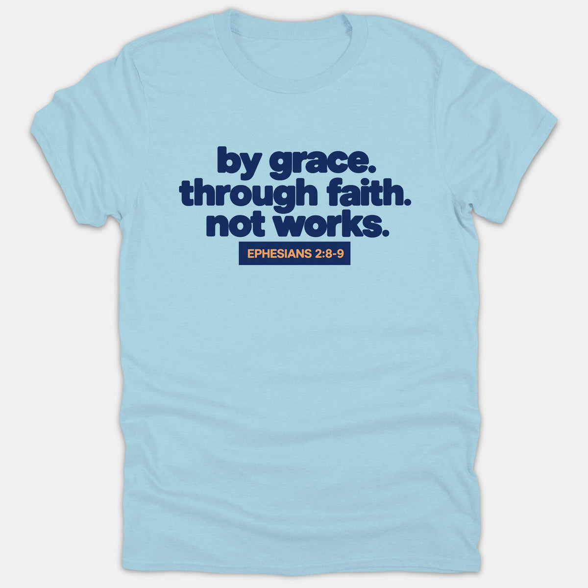 A light blue t-shirt featuring the phrase 'by grace. through faith. not works.' in bold navy text with the scripture reference 'EPHESIANS 2:8-9' in orange.