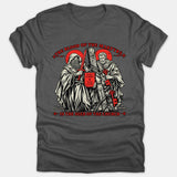 A dark gray Christian T-shirt featuring a detailed woodcut illustration of Saints Paul and Peter with red accents and text reading, 'The Blood of the Martyrs is the Seed of the Church.'