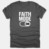 A dark gray t-shirt featuring bold white text that reads FAITH MODE above a graphic of a toggle switch set to the ON position.