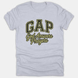 A light gray t-shirt featuring a varsity-style print that reads GAP God Answers Prayers in black and gold lettering across the chest.