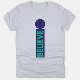 A light gray t-shirt featuring a graphic shaped like the letter I with a purple dot and a vertical rectangle containing the word BELIEVE in green.