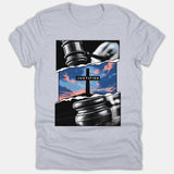 A light gray Christian t-shirt featuring a graphic design of a judge's gavel torn open to reveal a cross against a colorful sunset sky with the word JUSTIFIED.