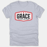 A light gray Christian t-shirt featuring a red framed badge design with three stars and bold text reading GRACE, God's Riches At Christ's Expense.
