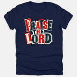 A navy blue Christian t-shirt featuring the phrase 'PRAISE THE LORD' in a bold collage cut-out style design with red, white, and dark blue block letters.