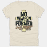 A beige Christian graphic t-shirt featuring a textured cross filled with mountain scenery and the scripture quote 'No Weapon Formed Shall Prosper Isaiah 54:17' in vintage style text.