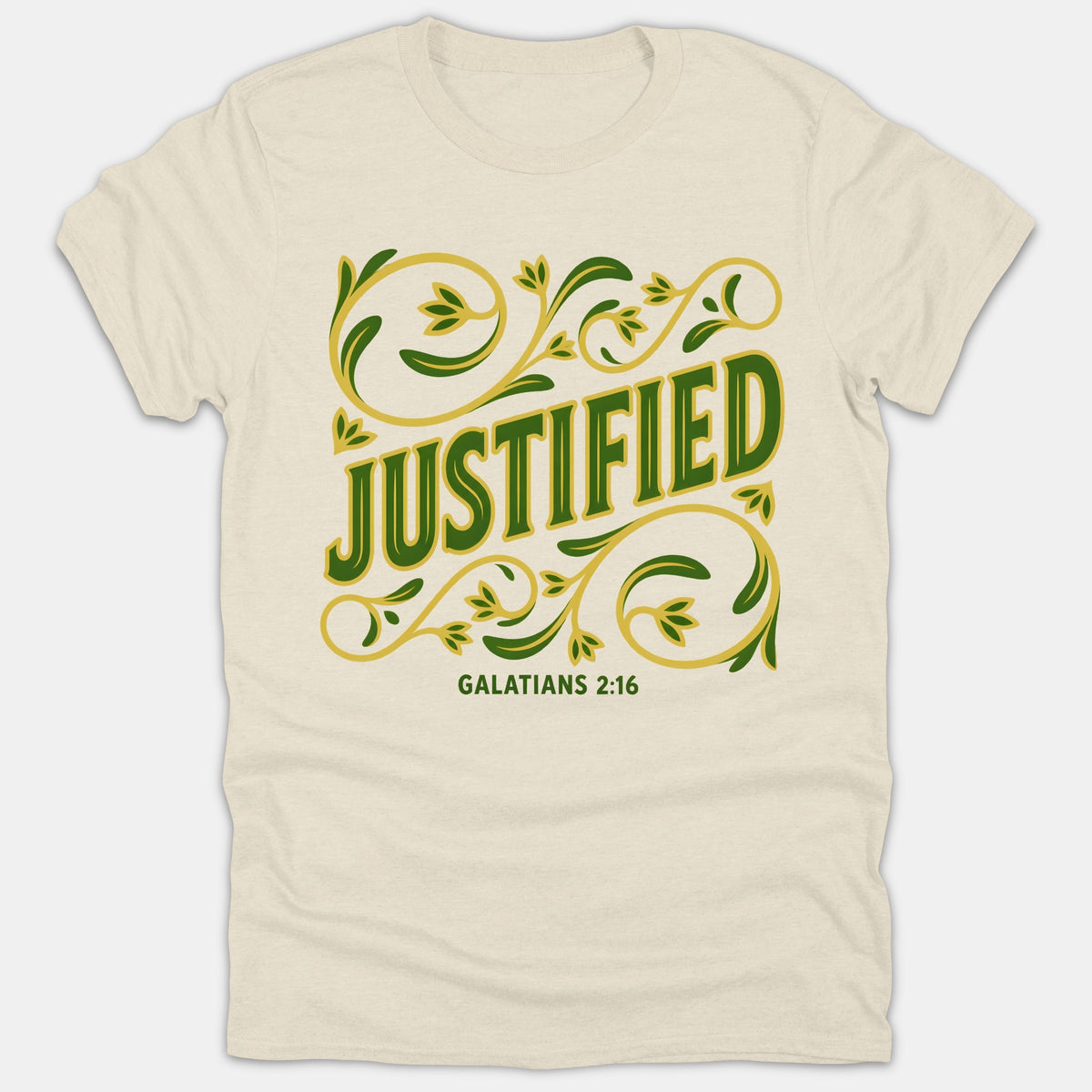 A beige Christian t-shirt featuring the word JUSTIFIED in green lettering surrounded by ornate gold and green floral flourishes above the scripture reference Galatians 2:16.