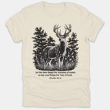 A beige Christian t-shirt featuring a detailed black graphic of a buck deer in a forest with the scripture from Psalm 42:1 printed below.
