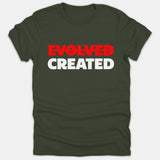 A dark green Christian t-shirt featuring the word EVOLVED crossed out in bold red text above the word CREATED in bold white letters.