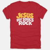 A red t-shirt featuring the Christian phrase 'JESUS MY SOUL'S ROCK' printed in bold retro yellow and white typography across the chest.