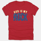 A red Christian t-shirt displaying the phrase 'GOD IS MY ROCK' in arched yellow lettering and textured blue block text.