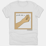 A white Christian t-shirt featuring a framed graphic with the text 'faith like a' next to a pinched hand gesture, labeled '( TO SCALE )' underneath.